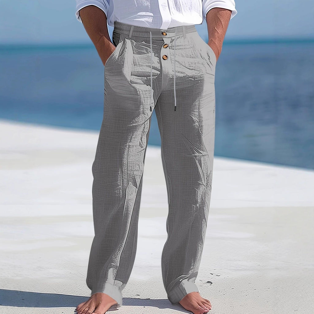 Person wearing gray pants with buttons standing on a white surface with a blue ocean background