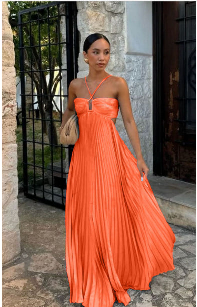 Woman in an orange dress standing outdoors near a stone building.