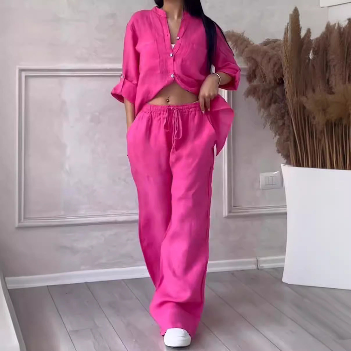 Person wearing a bright pink outfit in a room with decorative elements.