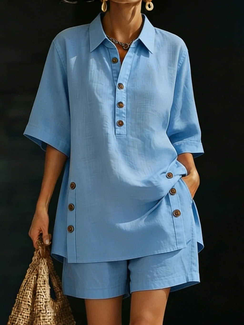Person wearing a blue outfit with buttons against a dark background