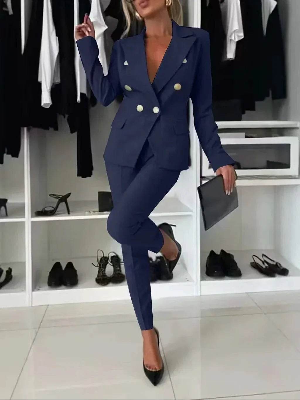 Woman modeling chic navy blue pantsuit with gold buttons from ZA-Zola, holding clutch, stylish wardrobe background