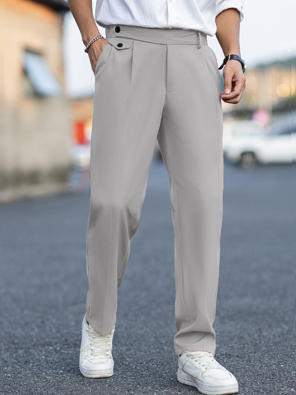 Person wearing light gray pants and white sneakers on a blurred street background