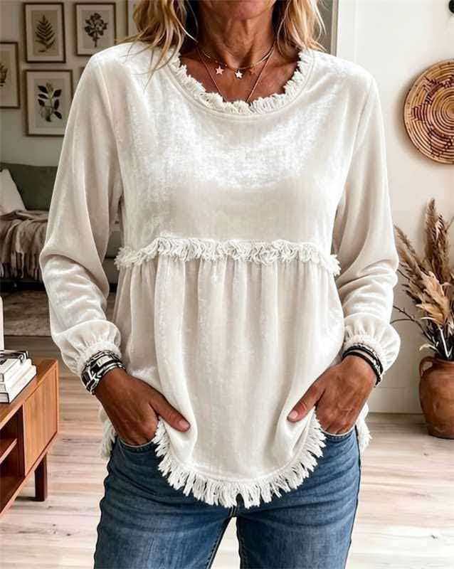 Woman wearing a white blouse with ruffled details and blue jeans in a living room setting.