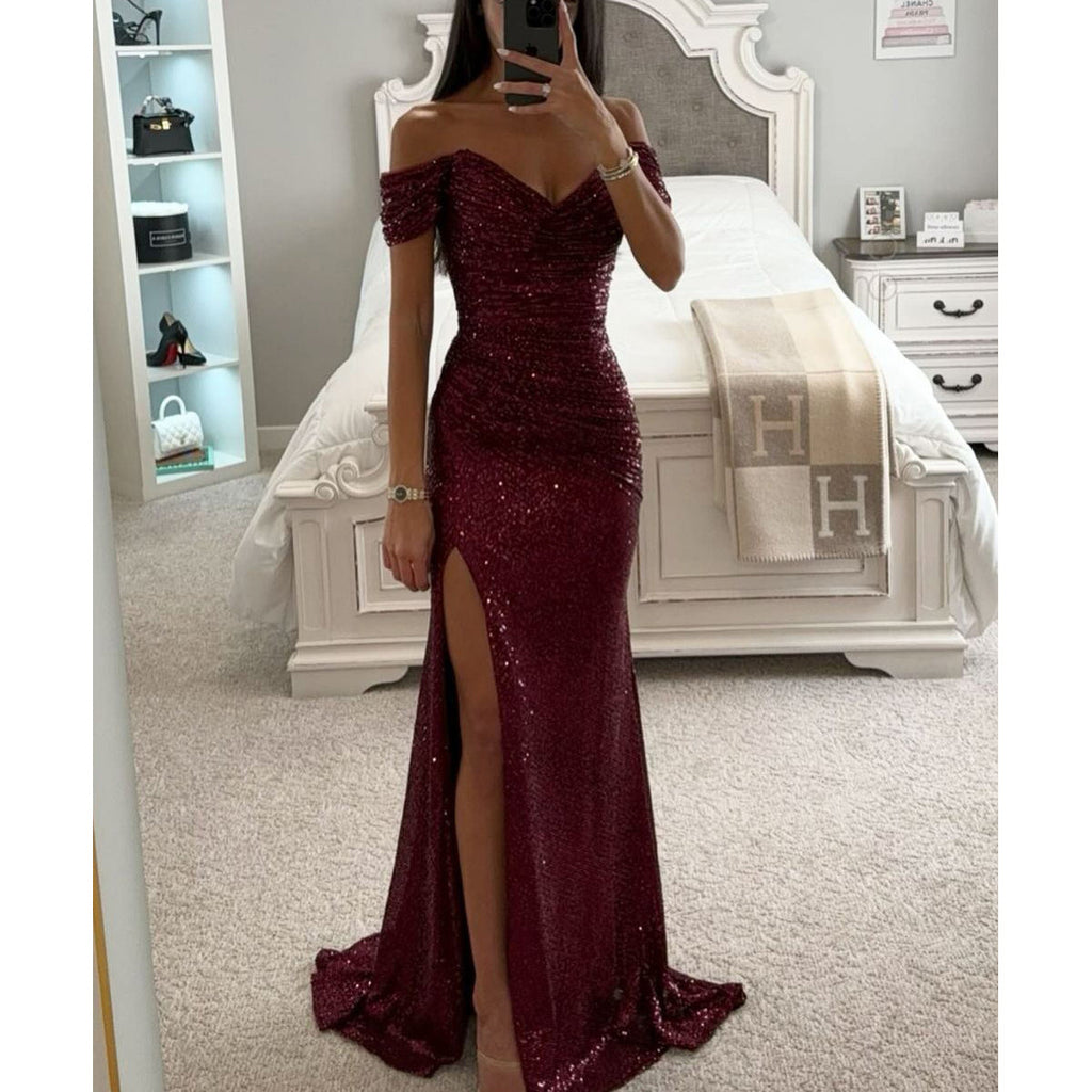 Person wearing a burgundy sequin dress with a slit in a bedroom setting