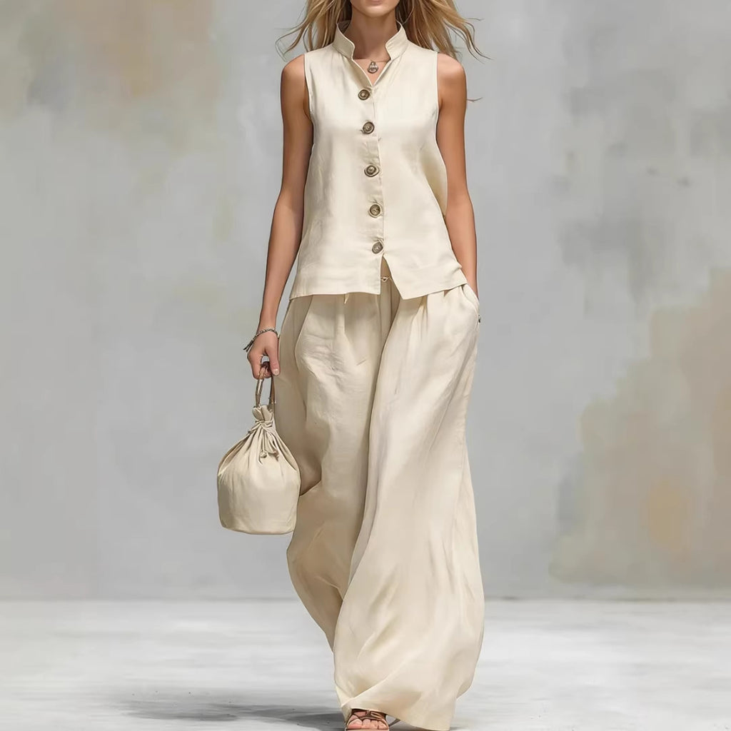 Woman wearing a beige sleeveless top and wide-leg pants holding a matching bag against a neutral background