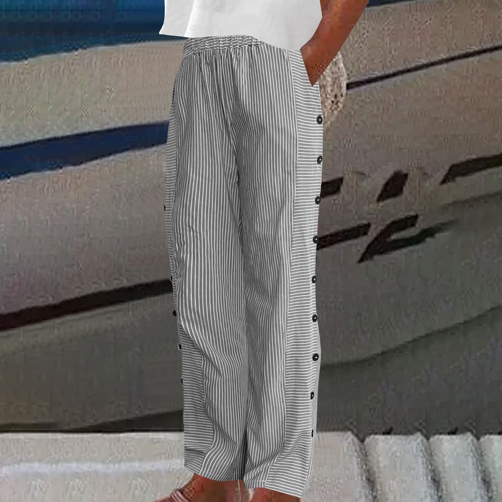 Person wearing a white shirt and striped pants with buttons against a blurred background