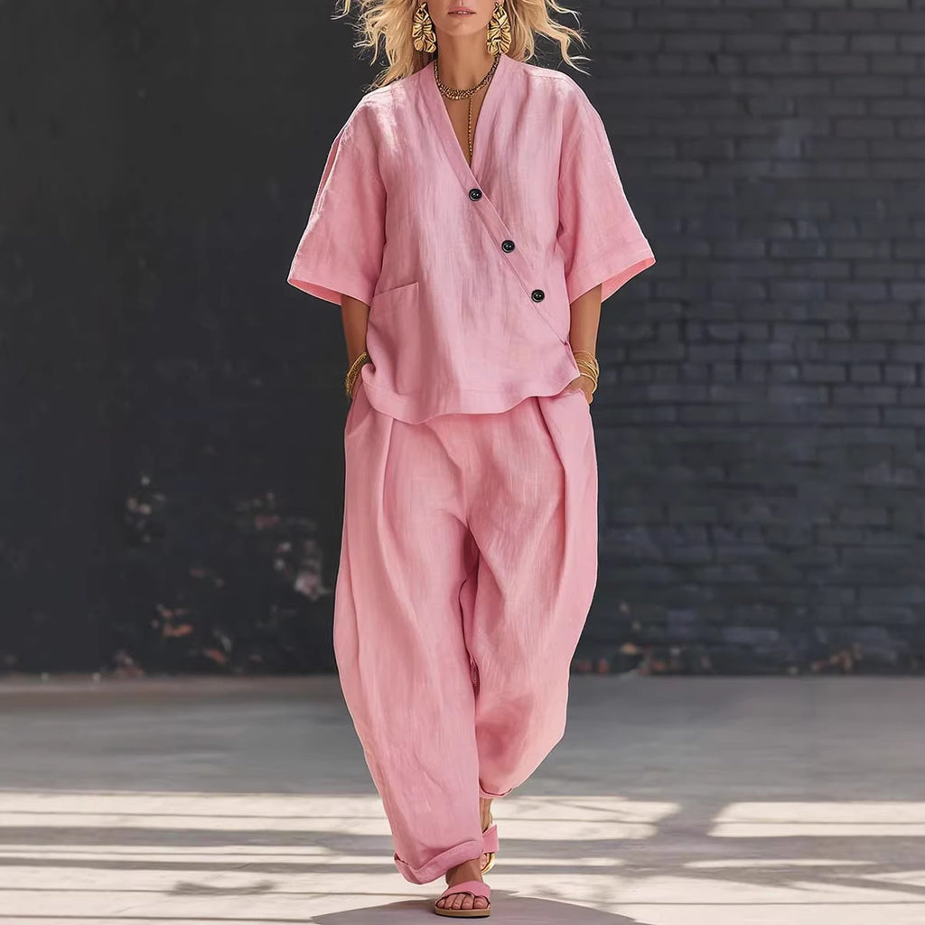 Person wearing a pink outfit standing against a dark brick wall.