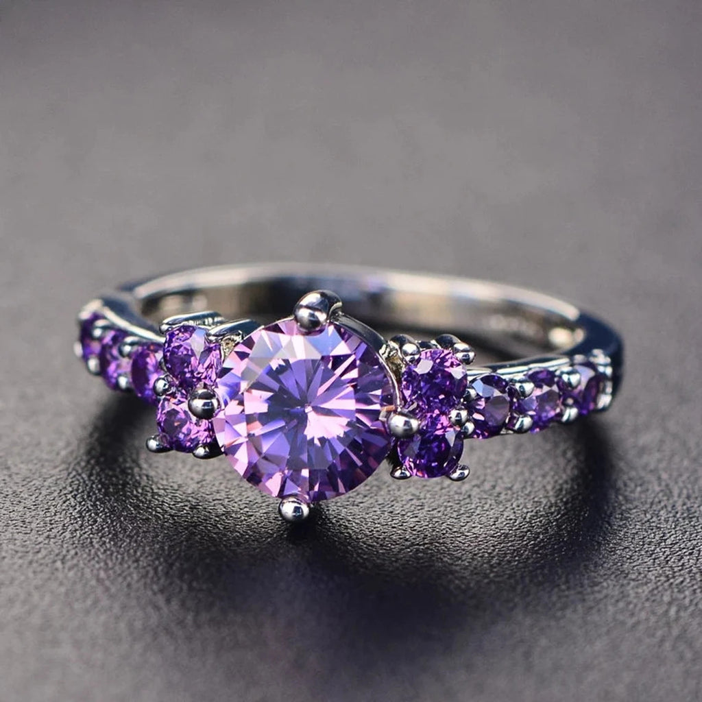 Silver ring with purple gemstones on a dark background