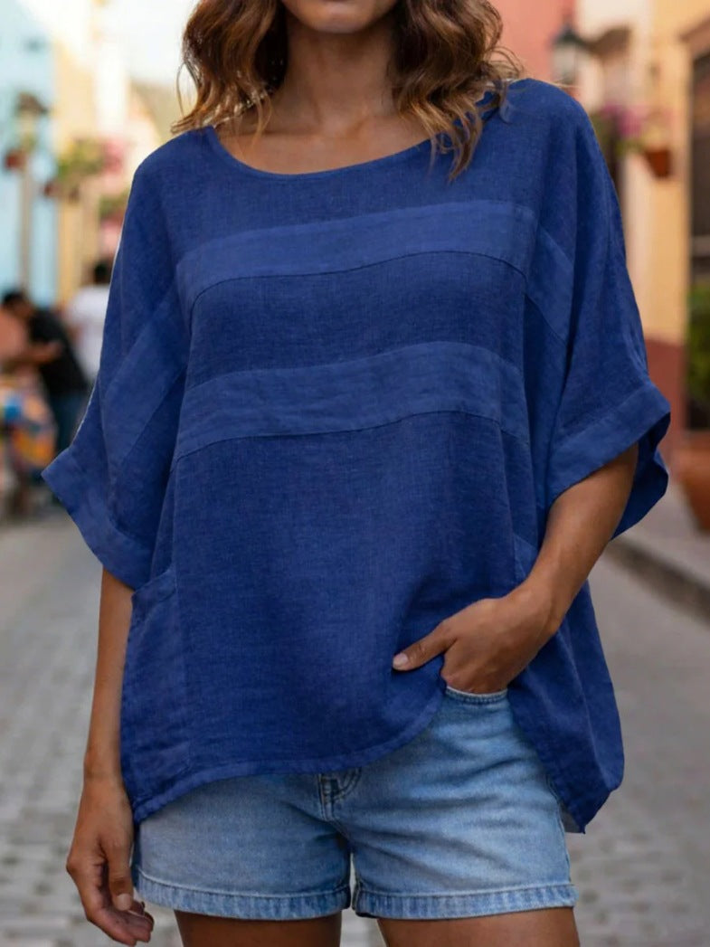 Person wearing a blue oversized top and denim shorts on a street.