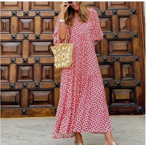 Woman in a red and white checkered dress holding a sunflower-patterned bag against a wooden background