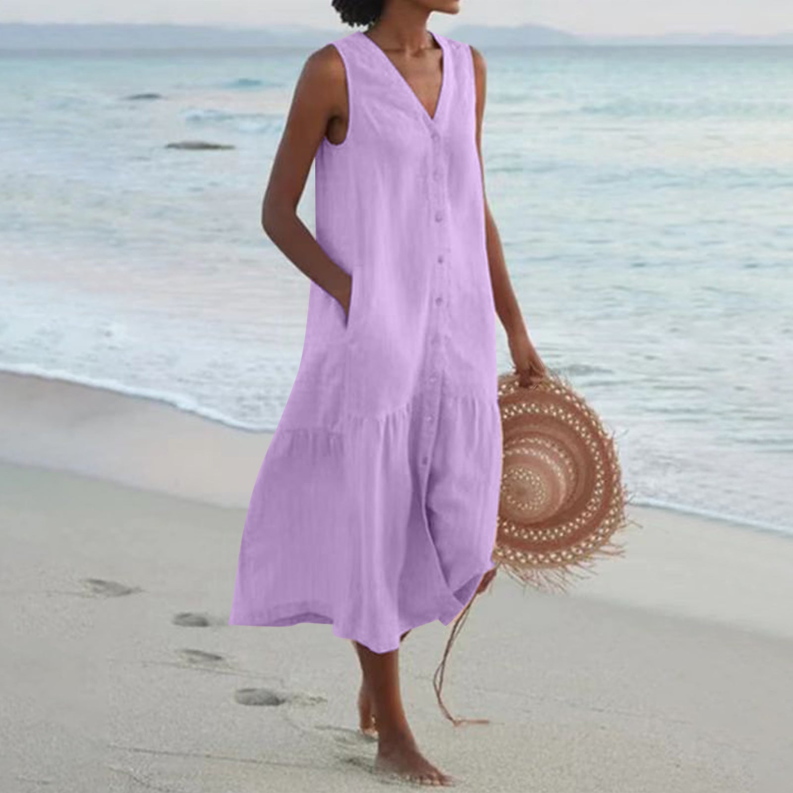 Woman in a purple dress holding a straw hat on a beach
