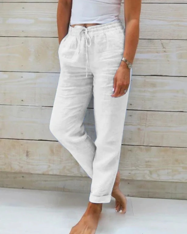 Person wearing white sweatpants against a wooden background