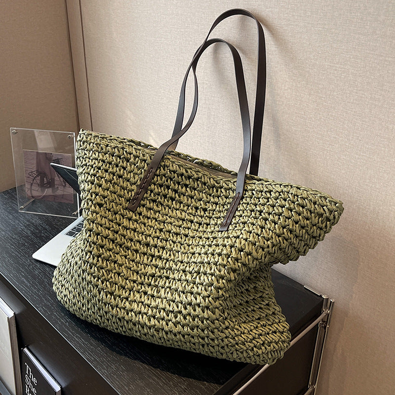 Green woven bag with brown straps on a wooden surface