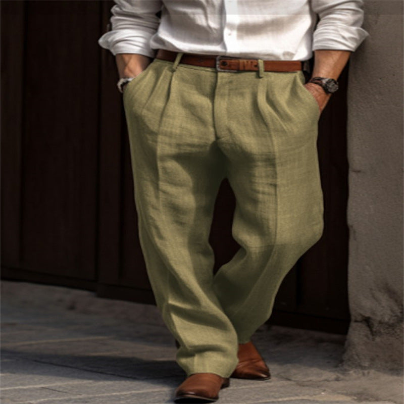 Person wearing green pants and a white shirt with a brown belt and shoes, standing against a dark background.