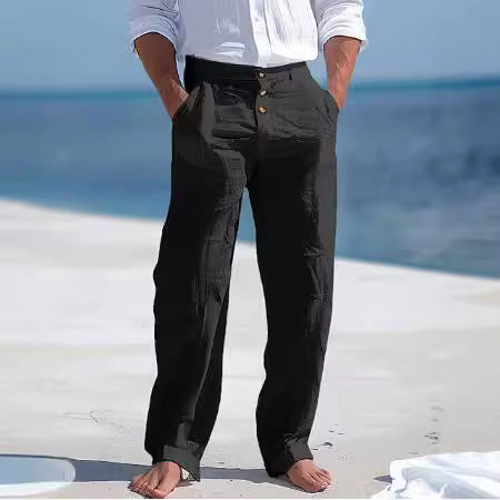 Person wearing black cargo pants standing on a beach with ocean in the background