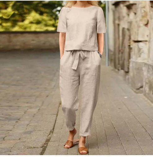 Person wearing a beige outfit walking on a stone path.