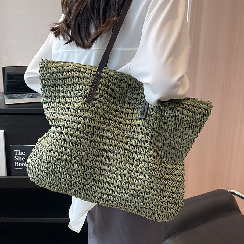 Person holding a green woven bag in an indoor setting