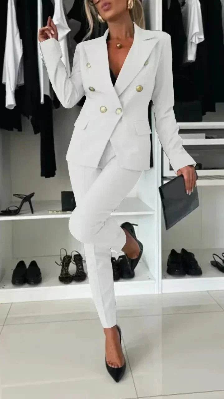 Woman in white double-breasted blazer suit with black heels, posing in modern closet