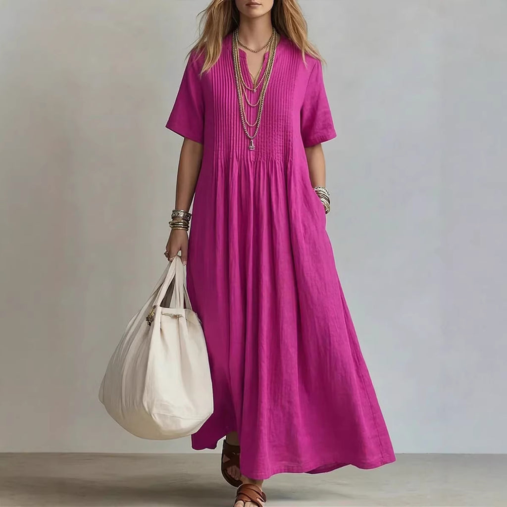 Woman wearing a long pink dress holding a white bag against a neutral background