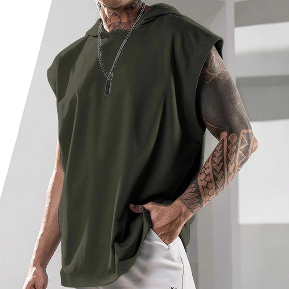 Person wearing a green sleeveless hoodie with tattoos on arms, standing against a light background.