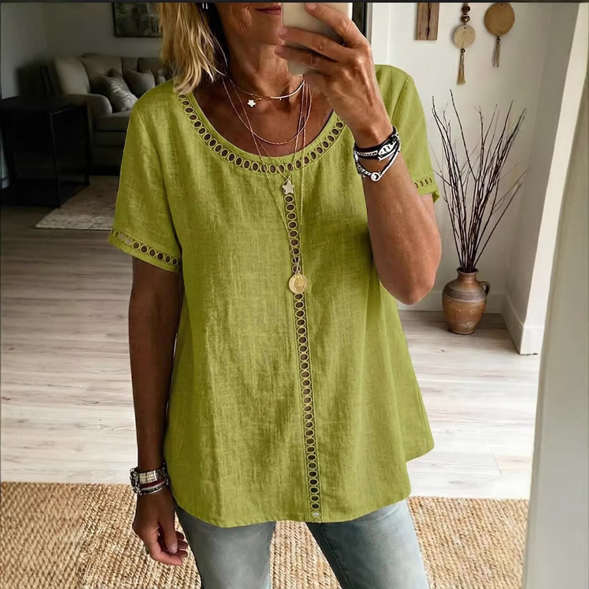 Person wearing a green top with decorative buttons in a living room setting.