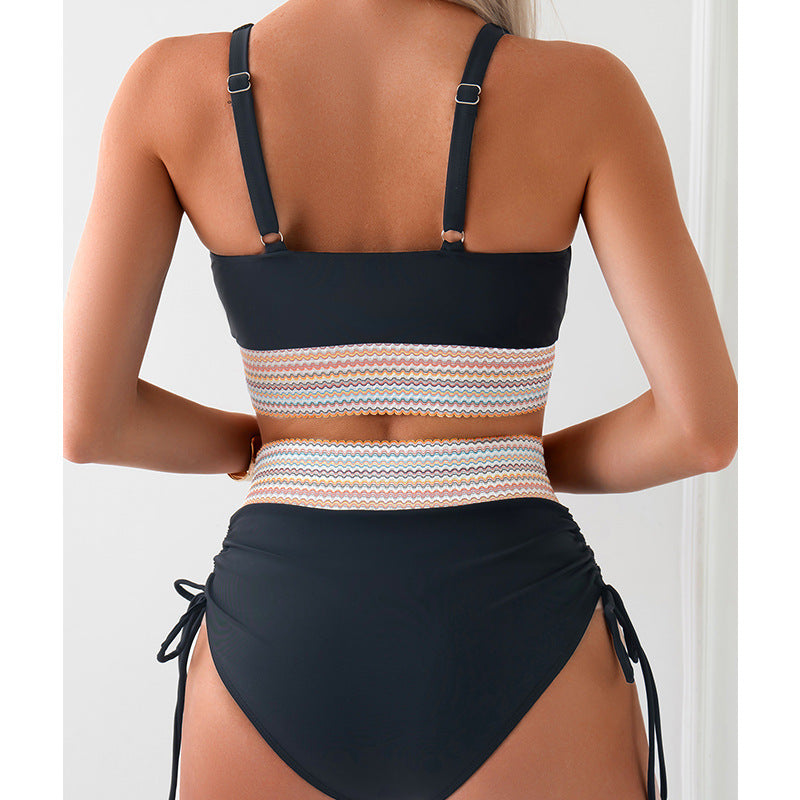Woman wearing a black and striped bikini top with a white background