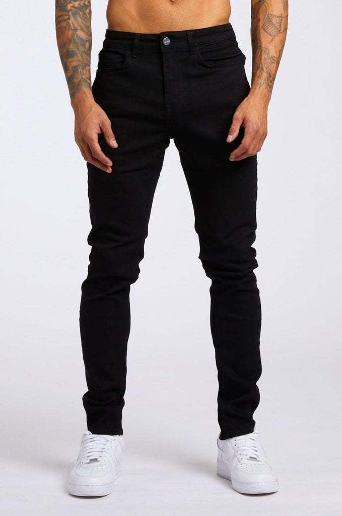 Person wearing black jeans and white sneakers on a white background
