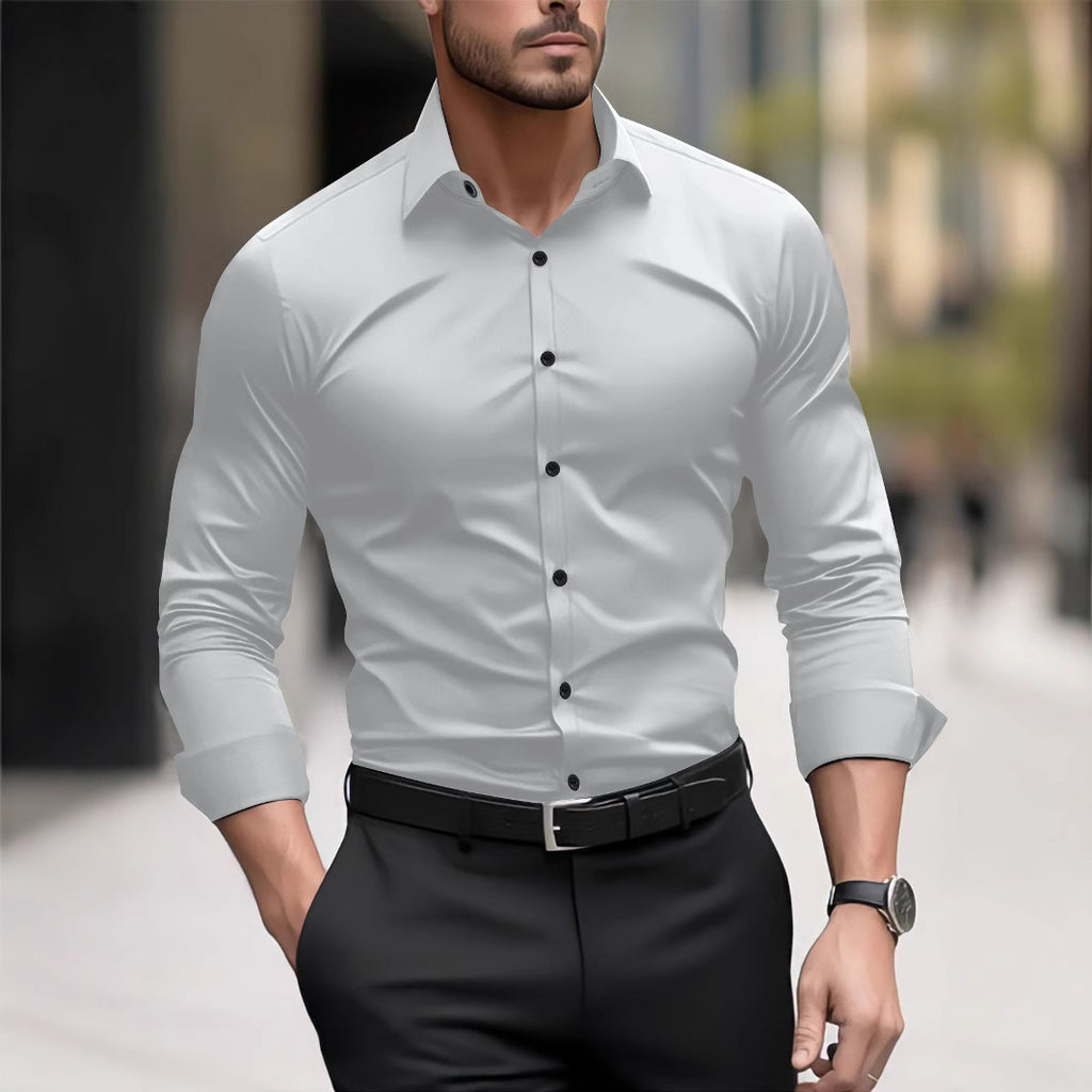 Man wearing a light gray dress shirt with black buttons and black pants on a blurred street background