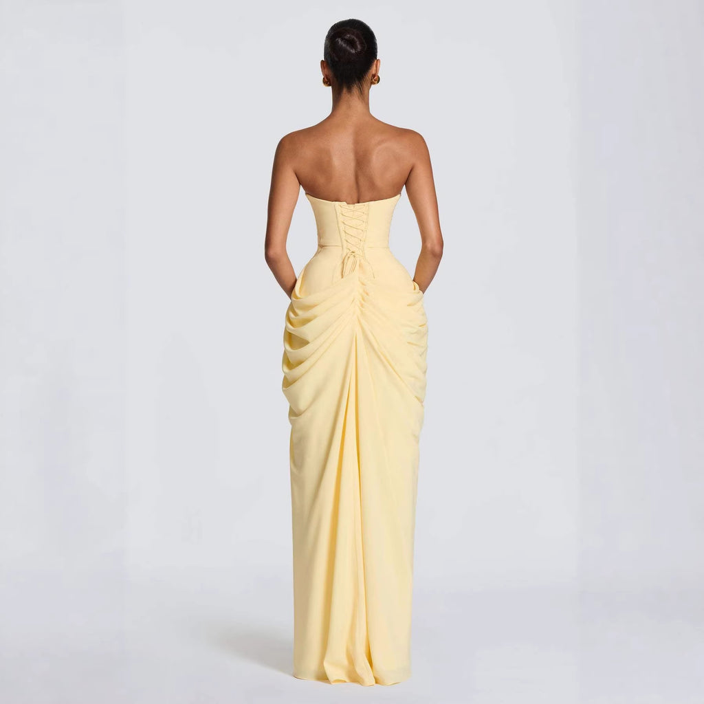 Woman wearing a yellow strapless gown with ruched detailing on a white background