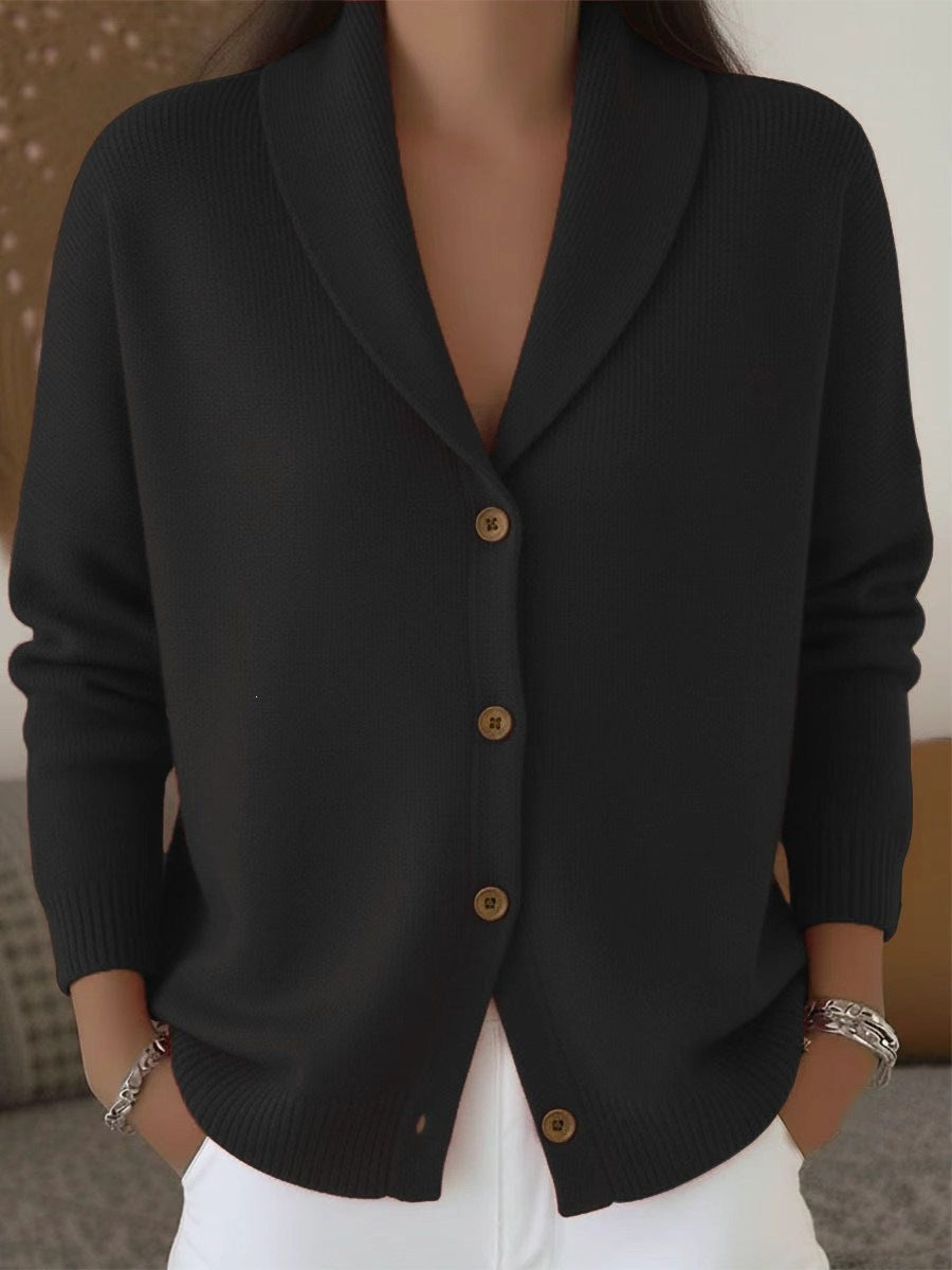 Black cardigan with brown buttons worn by a person, against a neutral background