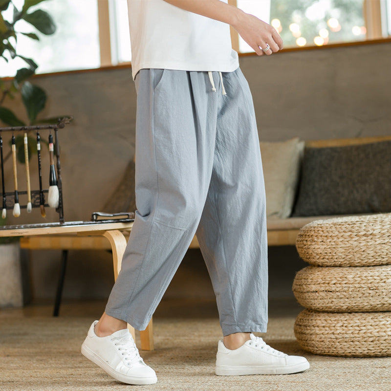 Person wearing light gray pants and white sneakers in a living room setting