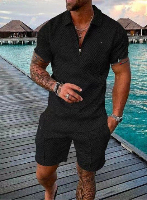 Man in black outfit standing on a dock with water and buildings in the background