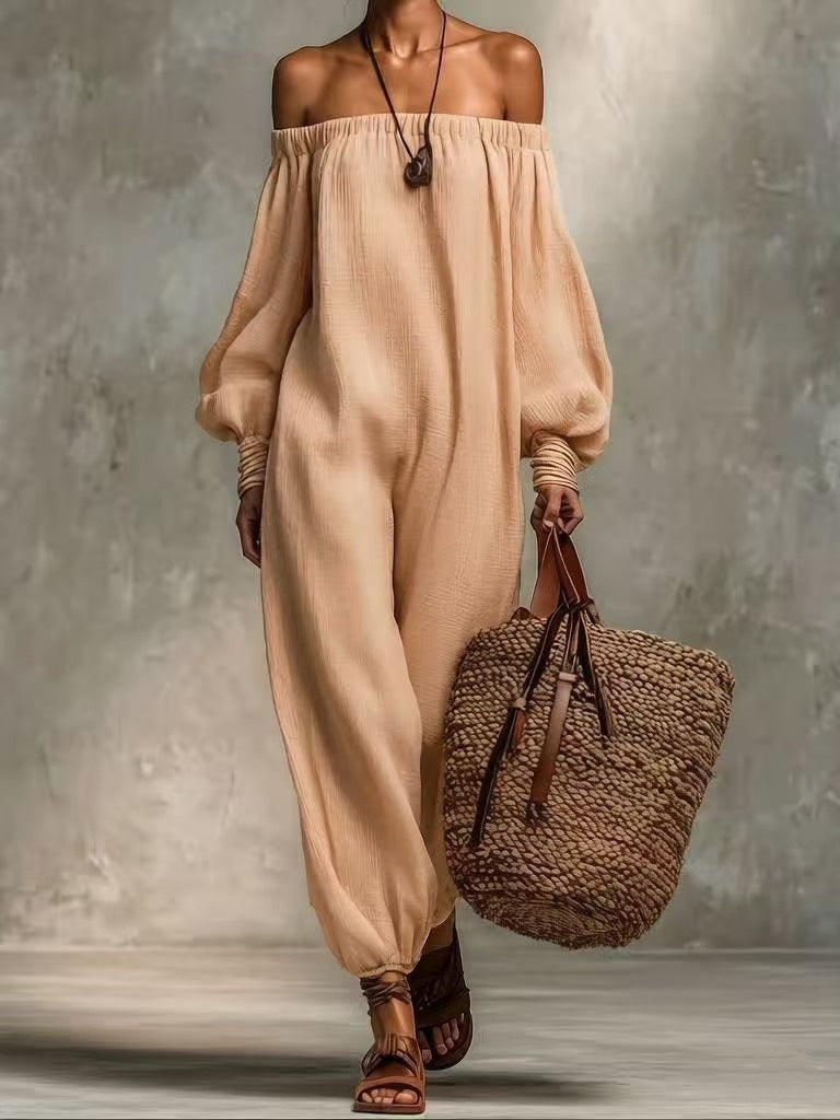 Woman wearing a beige off-shoulder outfit holding a woven bag against a neutral background