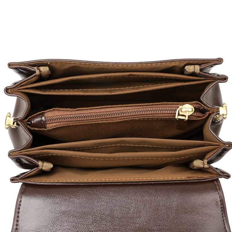 Brown leather handbag with multiple compartments and gold zippers on a white background