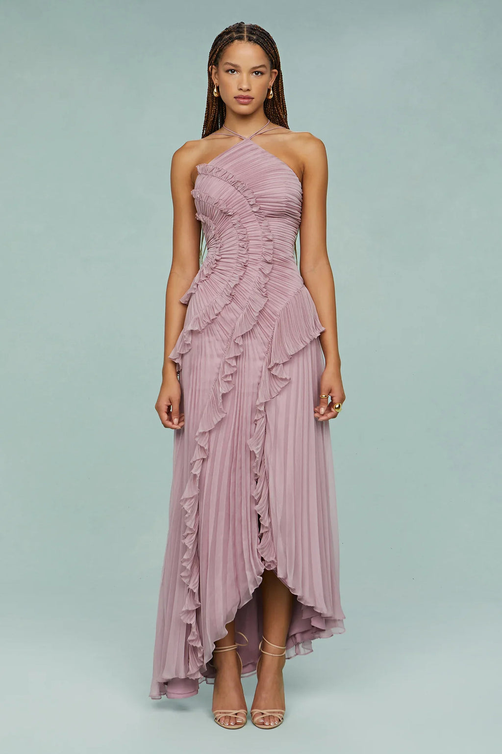 Woman wearing a pink one-shoulder dress with ruffled layers on a light gray background