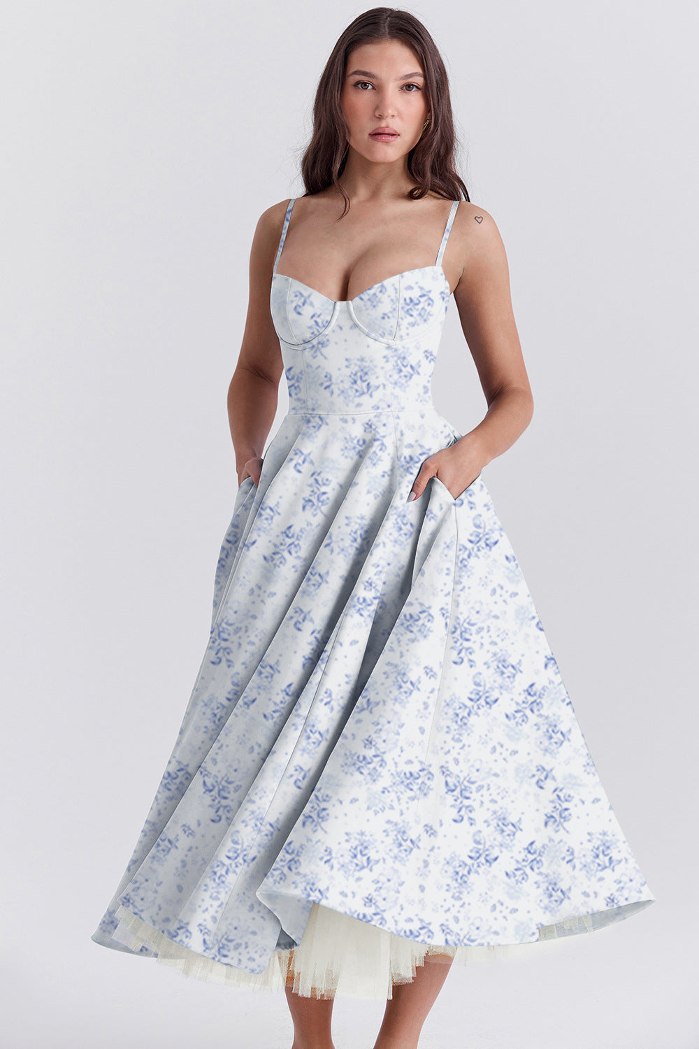 Woman wearing a white dress with blue floral pattern on a plain background