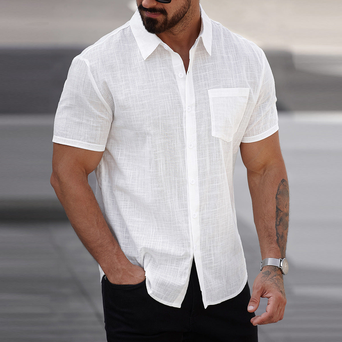 Man wearing a white short-sleeve linen shirt with a blurred background