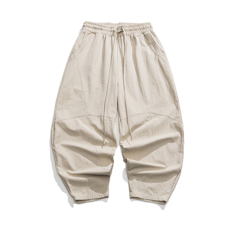 A pair of beige baggy drawstring pants with a relaxed, wide-leg silhouette, laid flat on a white background.