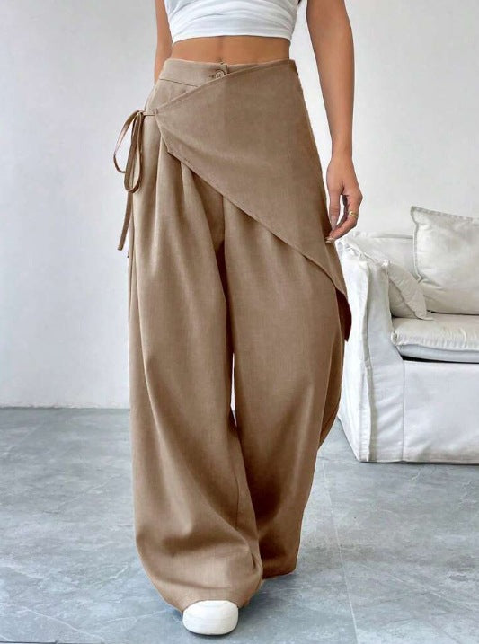 Person wearing brown wide-leg pants with a white top in a minimalistic room.