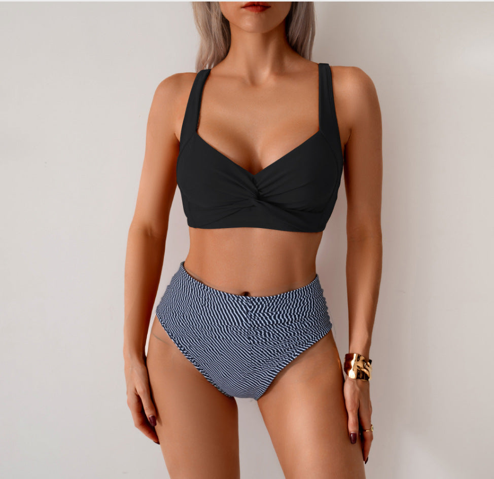 Woman wearing a black bikini top and patterned high-waisted bottom against a plain background
