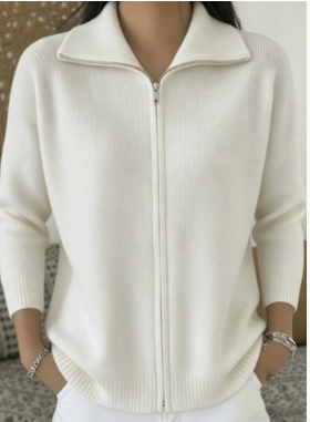 A person wearing a cream-colored ribbed knit zip-up sweater with a stand collar, shown from the neck down in a close-up shot.