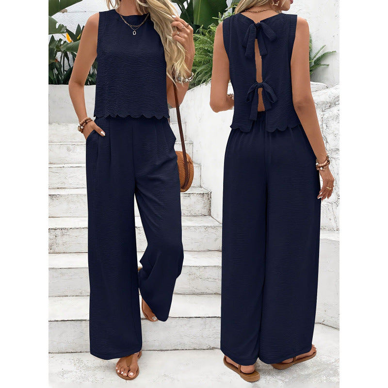 Woman wearing a navy blue jumpsuit with a scalloped hem design, standing on white steps.
