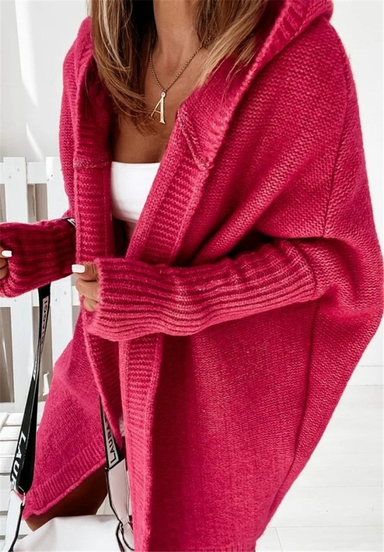 Person wearing a bright pink knitted cardigan with a white background