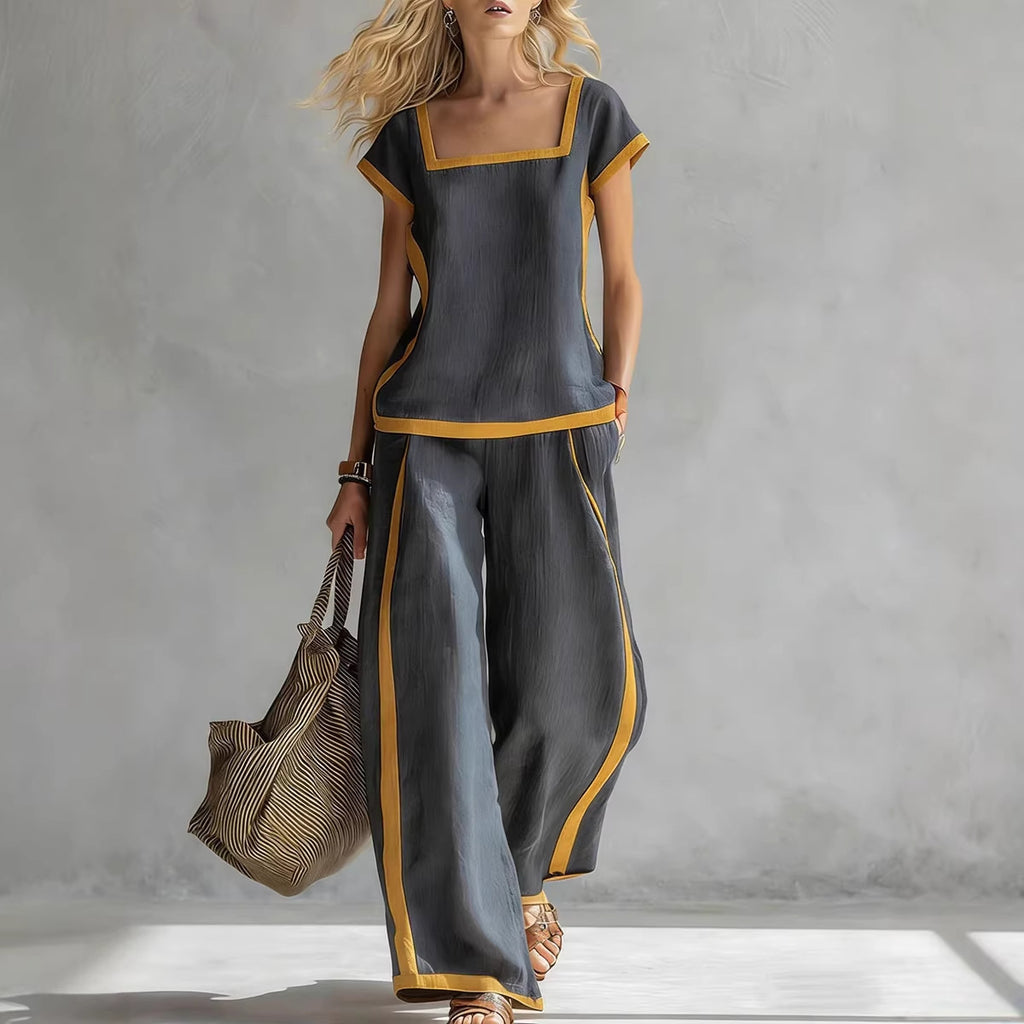 Woman wearing a gray outfit with yellow accents holding a bag against a gray background