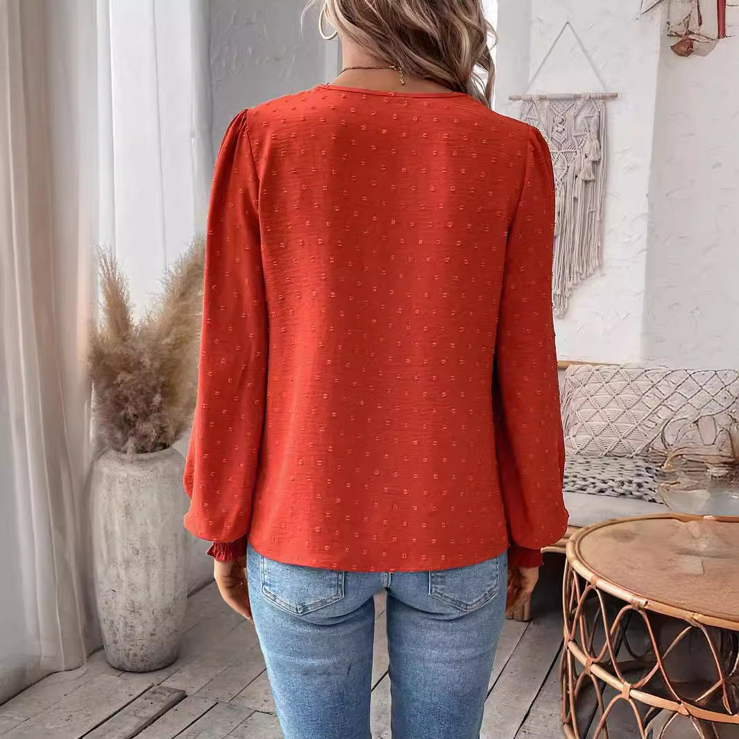Person wearing a red patterned top and blue jeans in a room with decor elements.
