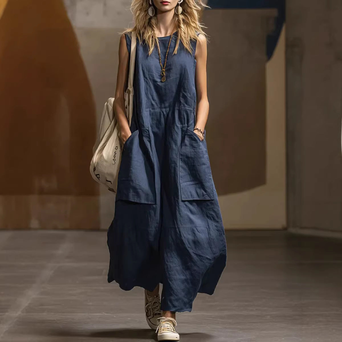 Woman wearing a blue dress with pockets, holding a beige bag, on a blurred street background.