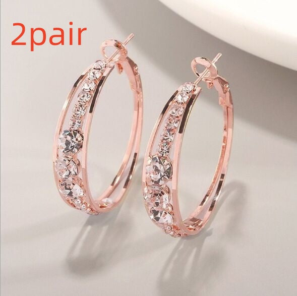 Rose gold hoop earrings with clear stones on a light gray background