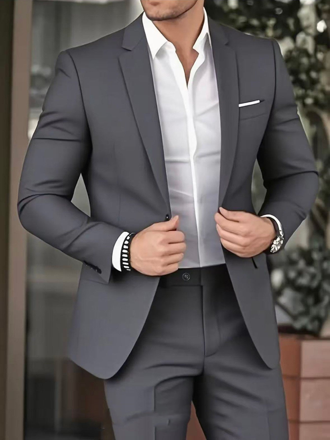 Man wearing a gray suit with a white shirt, standing outdoors.