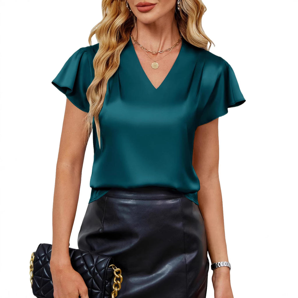 Woman wearing a teal top and black leather skirt with a blurred background