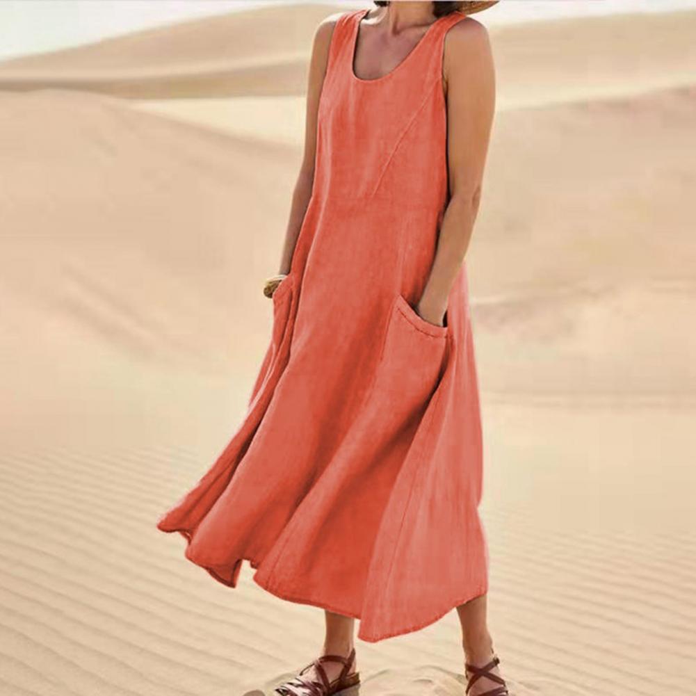 Person wearing a long orange dress standing in sand dunes